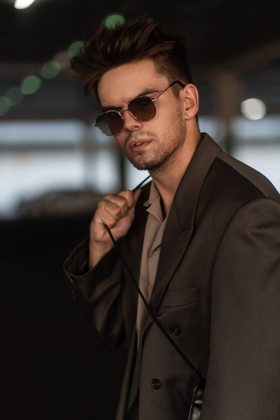 Modebewusster Geschäftsmann in Jacke und Hemd mit Sonnenbrille auf der Straße. Lässiger männlicher Stil und Mode - Foto, Bild