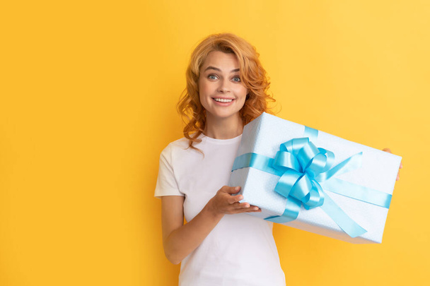 Lächelnde rothaarige Frau mit Geschenkbox auf gelbem Hintergrund. Alles Gute zum Geburtstag - Foto, Bild