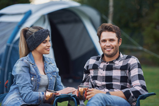 Kampta çadırın önünde sandalyede oturan genç ve hoş bir çift. - Fotoğraf, Görsel