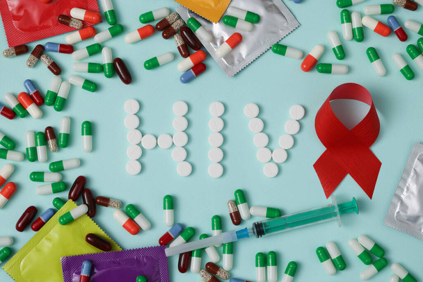 Het woord HIV is geschreven met pillen, rood lint - Foto, afbeelding