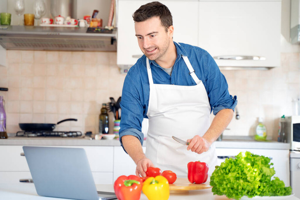 Un hombre está aprendiendo a cocinar viendo videos en línea - Foto, Imagen