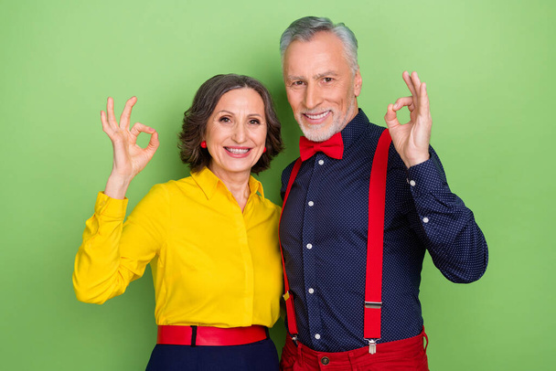 Photo of two satisfied attractive people fingers demonstrate okey approve symbol isolated on green color background - Fotó, kép