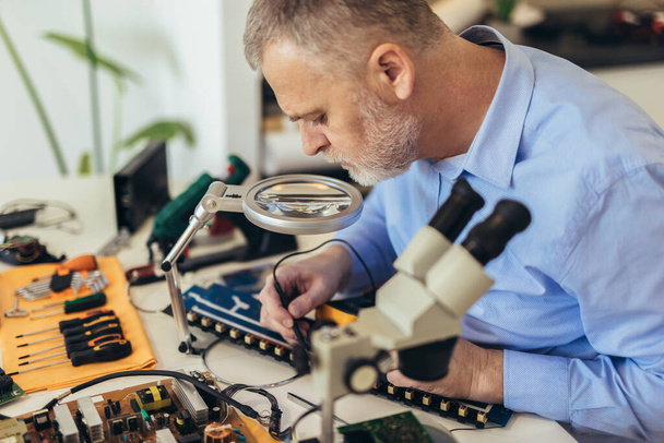 Ingenieur repariert kaputte Computergeräte. Elektronische Werkstatt, Technologieentwicklungskonzept - Foto, Bild
