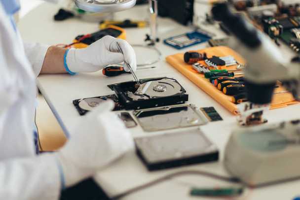 A mérnök megjavítja a törött merevlemezt. Elektronikus javítóműhely, technológiafejlesztési koncepció - Fotó, kép