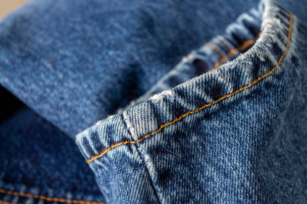 fragmento de calças jeans azuis costuradas com fios de laranja, foco seletivo - Foto, Imagem