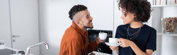 happy african american couple holding cups of coffee in kitchen, banner - Foto, Bild