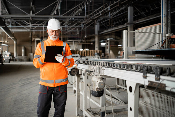 Ipari munkás felügyelő géppel készenlétben és a gyártás ellenőrzése a gyárban. - Fotó, kép