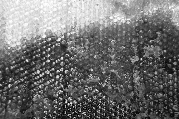 Druppel bijenhoning uit zeshoekige honingraten gevuld met gouden nectar, honingraten zomersamenstelling bestaande uit natuurlijke honing, druppel op was frame bij, druppel honing in honingraten - Foto, afbeelding