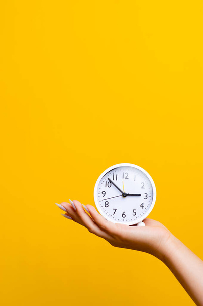 reloj despertador de mano y blanco sobre fondo amarillo con espacio para colocar texto en buen trabajo - Foto, imagen