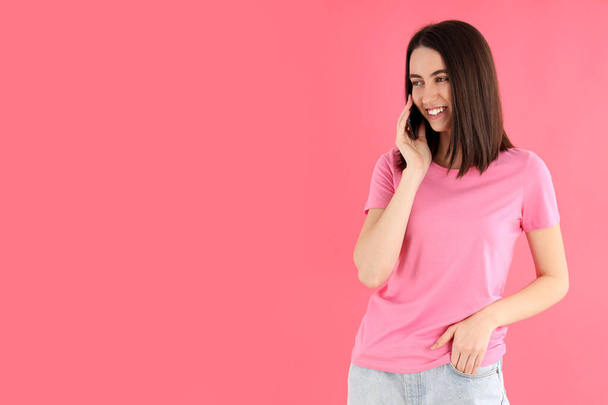 Женщина разговаривает по телефону на розовом фоне - Фото, изображение