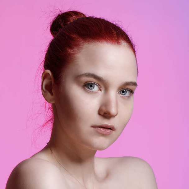 Portrait of a beautiful young woman with clear skin and natural makeup on a pink background. - Photo, image
