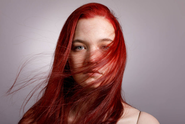 風に流れる髪の若い赤髪の女性の肖像画. - 写真・画像