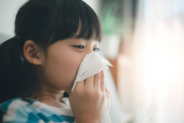 Ongezond kind blaast neus in weefsel, kind lijdt aan loopneus of niezen, Een meisje vat een kou wanneer het seizoen te veranderen, jeugd vegen neus met weefsel - Foto, afbeelding