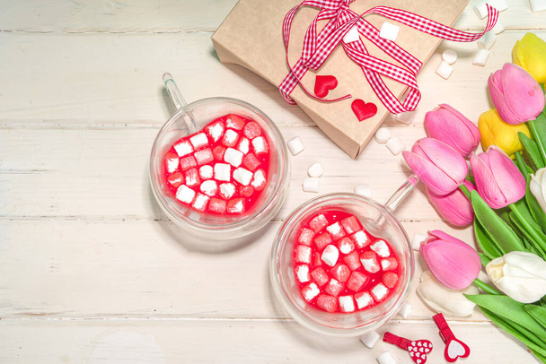 Herzförmige Tasse mit roter Samt-Schokolade, mit kleinen Marshmallows, Geschenkbox und Blumen zum Valentinstag - Foto, Bild