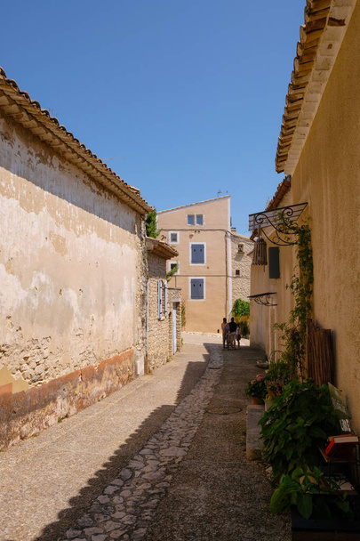Joucas, Provence, France. August 08, 2021. Old stone street with tourist family and street's library. Local tourism. Vertical image. - Foto, Imagen