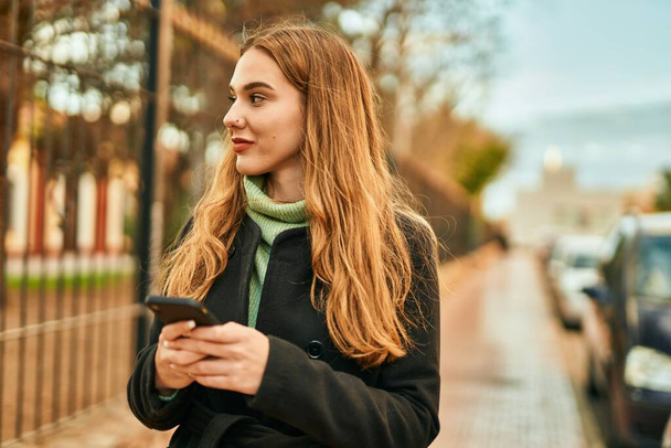 Young blonde girl smiling happy using smartphone at the city. - Foto, immagini