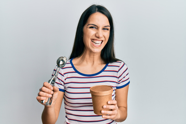 Nuori latino nainen tilalla jäätelöä hymyilee ja nauraa kovaa ääneen, koska hauska hullu vitsi.  - Valokuva, kuva