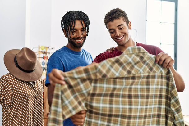 Δύο άνδρες φίλοι επιλέγουν ρούχα κρατώντας πουκάμισο στο κατάστημα ρούχων - Φωτογραφία, εικόνα