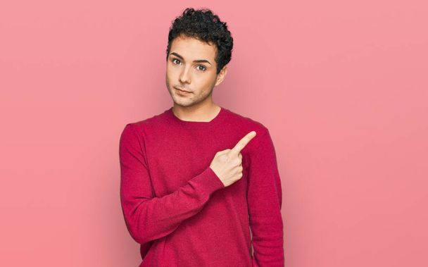 Fiatal jóképű férfi alkalmi ruhát visel mutató kéz ujját oldalra mutató reklám, komoly és nyugodt arc  - Fotó, kép
