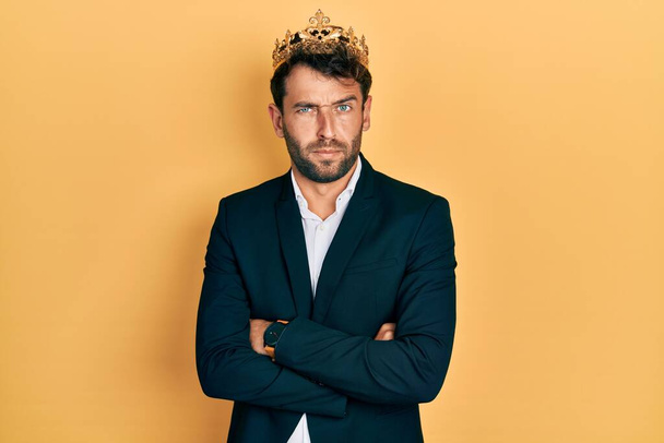 Handsome man with beard wearing business suit with arms crossed gesture and king crown skeptic and nervous, frowning upset because of problem. negative person.  - Foto, Bild