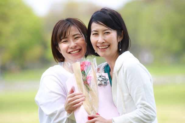 two asian women with present and flower - Fotografie, Obrázek