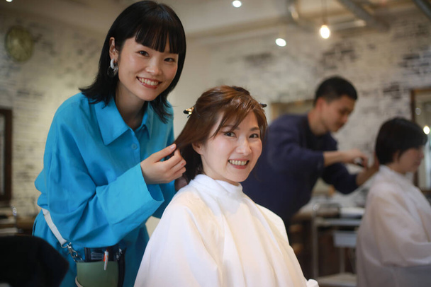 Збільшений портрет азійських перукарів, що створює новий стиль волосся для клієнта. - Фото, зображення