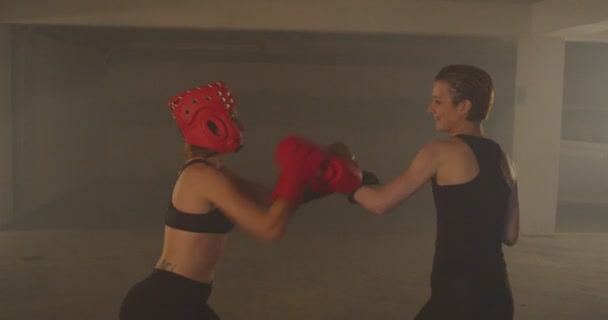 Dos chicas fuertes sonríen mientras tienen una pelea en su entrenamiento - Metraje, vídeo