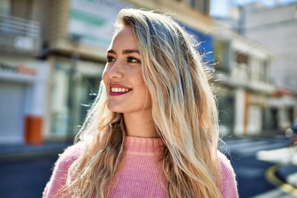 Young blonde woman smiling at the city - Photo, image