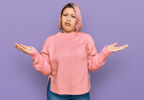 Испанская женщина с розовыми волосами носить случайные зимний свитер невежественный и путают с открытыми объятиями, понятия не имею.  - Фото, изображение
