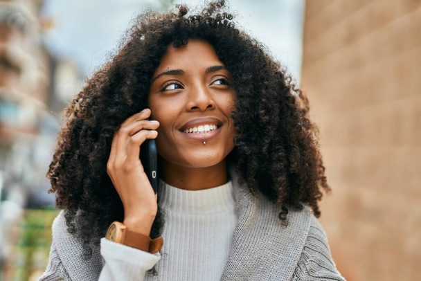 Mladý africký Američan žena usměvavý šťastný mluvení na smartphone ve městě. - Fotografie, Obrázek
