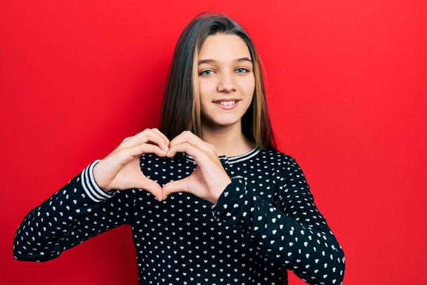 Young brunette girl wearing casual sweater smiling in love showing heart symbol and shape with hands. romantic concept.  - Photo, image