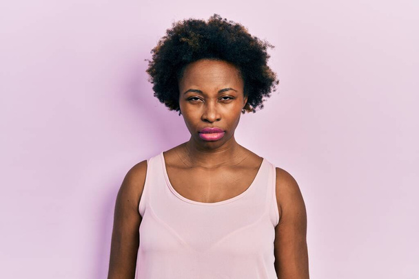 Νεαρή Αφροαμερικάνα που φοράει ανέμελα αμάνικα μπλουζάκια σκεπτική και νευρική, συνοφρυωμένη λόγω προβλήματος. αρνητικό πρόσωπο.  - Φωτογραφία, εικόνα