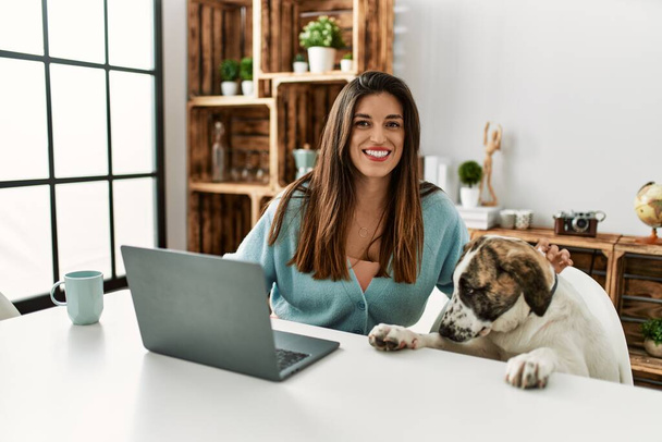 Young woman using laptop sitting on table with dog at home - Fotografie, Obrázek