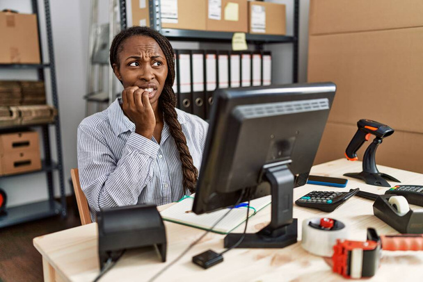 Αφρικανική γυναίκα που εργάζεται σε μικρές επιχειρήσεις ηλεκτρονικού εμπορίου αναζητούν τόνισε και νευρικό με τα χέρια στο στόμα τρώει τα νύχια. πρόβλημα άγχους.  - Φωτογραφία, εικόνα