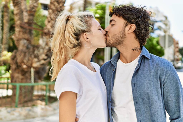 Jeune beau couple de petite amie caucasienne et petit ami hispanique embrasser en plein air par une journée ensoleillée. Femme et homme souriant heureux sortir ensemble relation - Photo, image