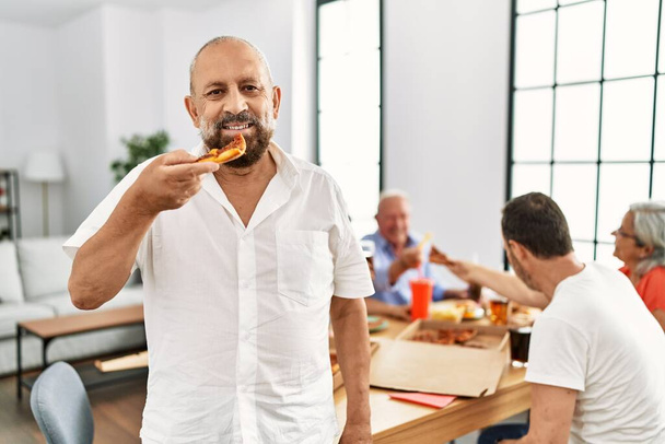 Középkorú emberek csoportja mosolyognak boldog eszik olasz pizza ül az asztalon otthon - Fotó, kép