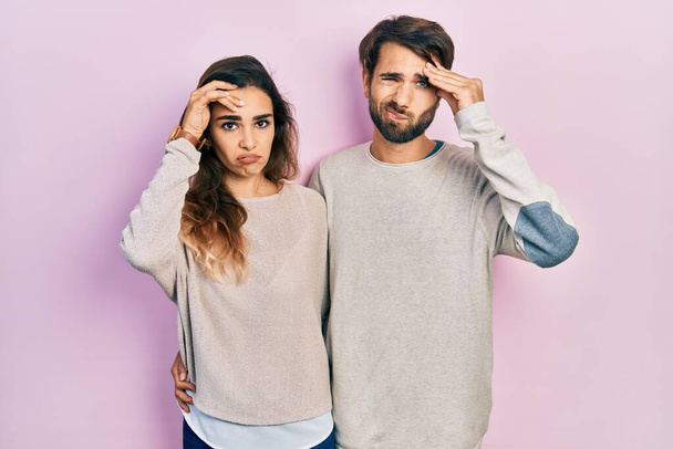 Молодая испаноязычная пара в повседневной одежде беспокоилась и переживала о проблеме с рукой на лбу, нервничала и беспокоилась о кризисе.  - Фото, изображение