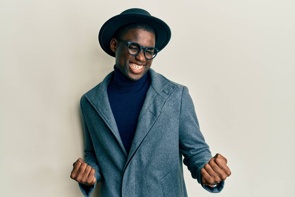 Fiatal afro-amerikai férfi visel elegáns stílus nagyon boldog és izgatott csinál győztes gesztus felemelt karokkal, mosolygós és sikoltozó siker. ünnepség koncepciója.  - Fotó, kép