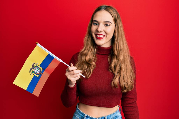 Mladá blondýnka drží ecuador vlajku vypadá pozitivní a šťastný stojící a usmívá se s sebevědomým úsměvem ukazující zuby  - Fotografie, Obrázek