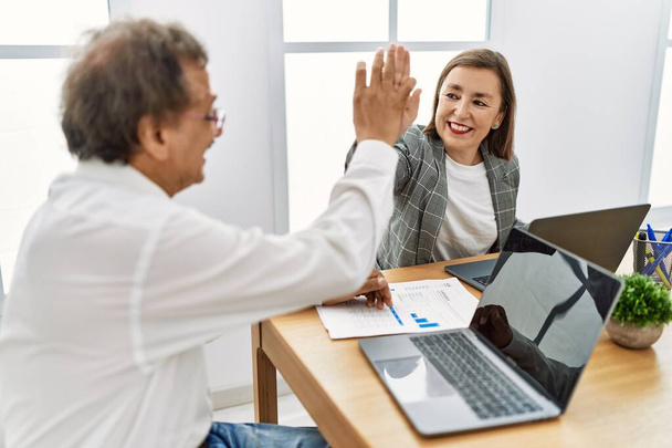 Чоловік і жінка середнього віку бізнесмени високі п'ять піднятих рук, що працюють в офісі
 - Фото, зображення