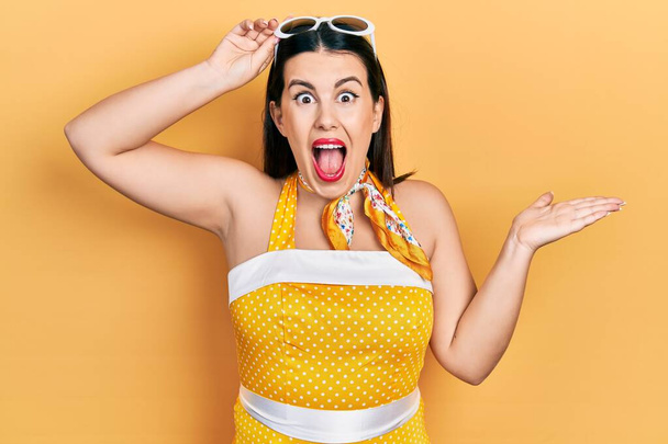 Young hispanic woman wearing pin up style celebrating victory with happy smile and winner expression with raised hands  - Photo, Image