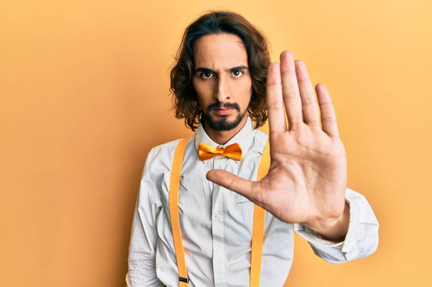 Young hispanic man wearing hipster elegant look doing stop sing with palm of the hand. warning expression with negative and serious gesture on the face.  - Valokuva, kuva