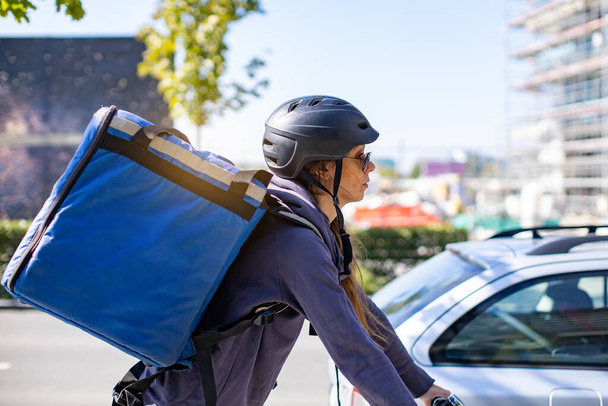delivery woman riding electric bicycle in city - Foto, imagen