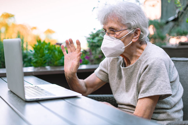 old woman with face mask using laptop to chat via internet - Foto, Imagem
