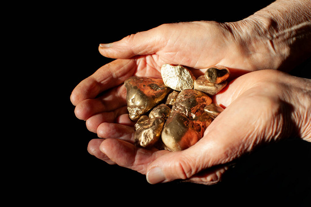 many large golden nuggets in elderly woman's hands - Foto, afbeelding