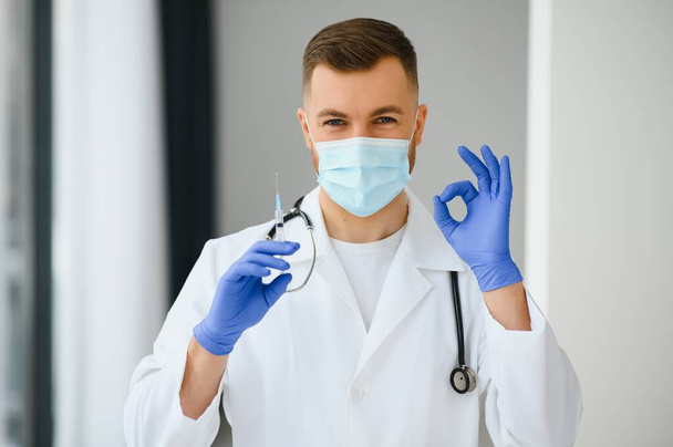 A doctor in blue gloves holding a bottle with vaccine. Close up shot. Medicine and healthcare concept - Foto, immagini