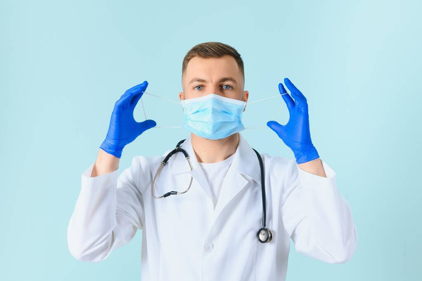 Male doctor in medical mask on color background - Foto, imagen