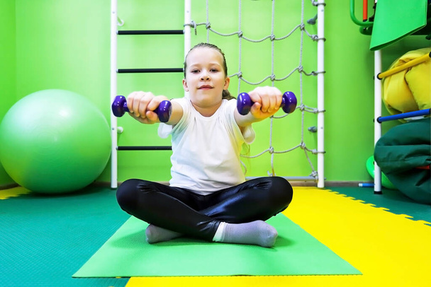 Little girl goes in for sports in special tight clothes in the children's center and leads a healthy lifestyle - Zdjęcie, obraz