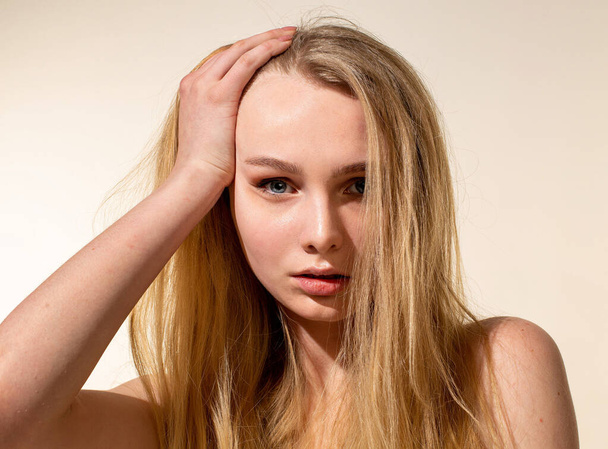 Young woman with blonde hair isolated on beige portrait - 写真・画像