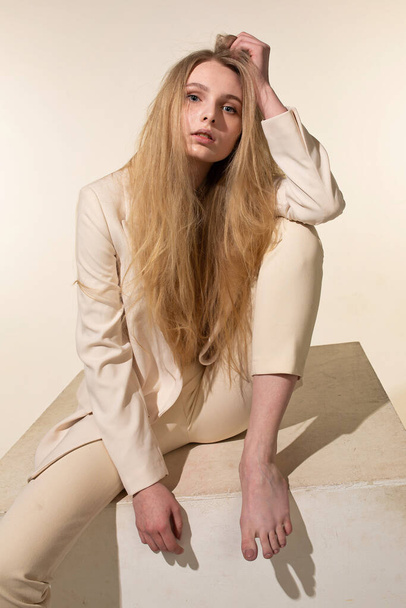 Young woman with blonde hair isolated on beige with long hair - Fotografie, Obrázek